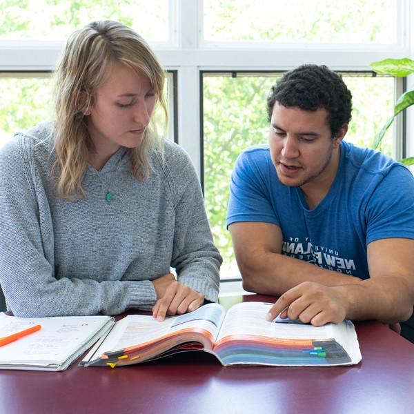 Two students studying out of a shared book